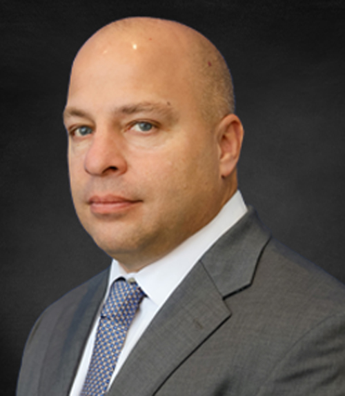 Jerret Giammichele, Vice President of Sales and Marketing, wearing a gray suit, standing in front of a gray background